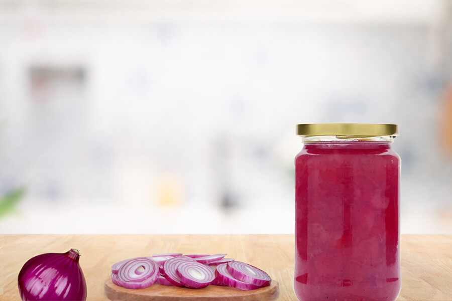 Marmellata di cipolle rosse Immagini mood: barattolo di vetro con marmellata di cipolle rosse disposto accanto a un tagliere con cipolle affettate