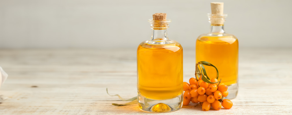 Ricette di liquori Ricette di liquori per la categoria banner: due bottiglie di liquore riempite con liquore all'olivello spinoso, decorate con bacche di olivello spinoso, chiuse con tappi di sughero