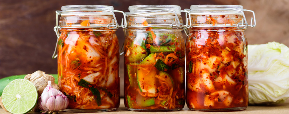 Fermentazione delle verdure Immagine d'atmosfera: gruppo di tre barattoli con struttura in filo metallico riempiti di verdure fermentate