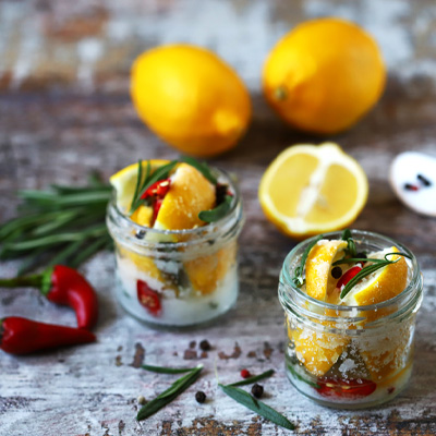 Guida "Conservazione degli alimenti sotto sale": anteprima dell'immagine dei barattoli con limoni e spezie sotto sale
