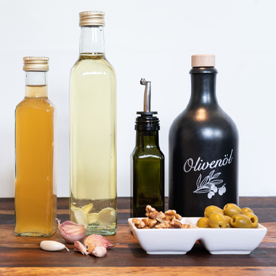 Anteprima immagine "Produrre aceto e olio": bottiglie d'olio riempite e decorate con aglio, noci e olive