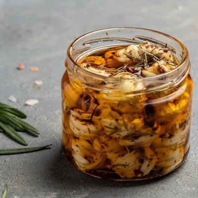 Guida alla conservazione sott'olio Immagine guida "conservazione sott'olio": verdure sott'olio ed erbe aromatiche in un barattolo a vite