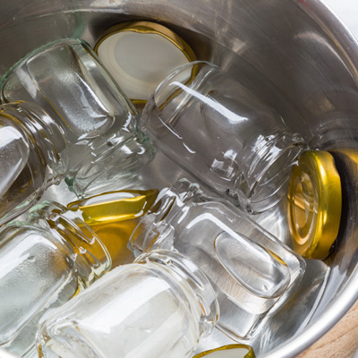 Guida alla sterilizzazione Immagine di anteprima della guida "Sterilizzazione": barattoli e coperchi a vite sono immersi in una pentola d'acqua