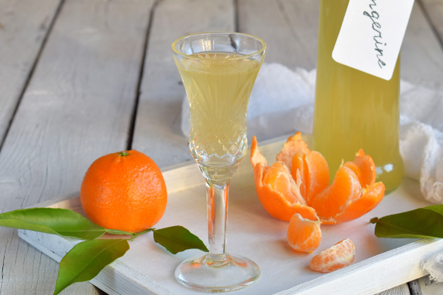 Ricetta del liquore al mandarino Immagine d'atmosfera: liquore al mandarino in un bicchiere da liquore, disposto con mandarini
