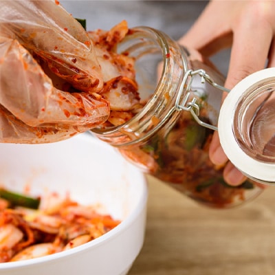 Fermentazione delle verdure Una persona riempie un barattolo con fondo di filo con delle verdure fermentate