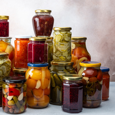 Immagine d'atmosfera: un sacco di barattoli di conserva impilati con vari contenuti su uno sfondo chiaro