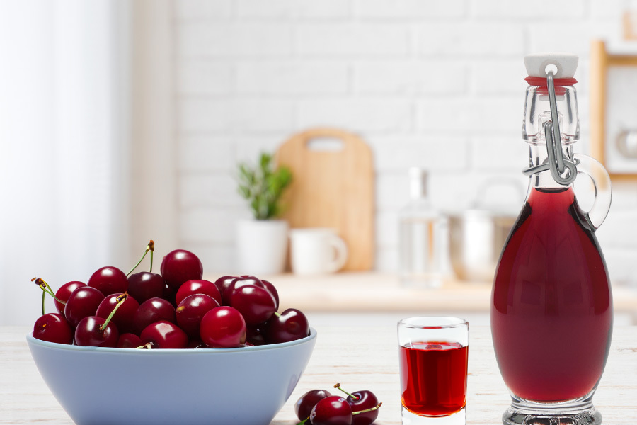 Immagine d'atmosfera: una bottiglia di liquore è riempita e circondata da ciliegie