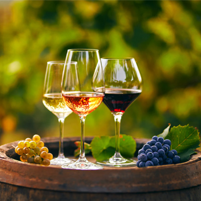 Classificazione dei vitigni in Europa Immagine d'atmosfera: tre bicchieri di vino pieni su una botte di vino con la natura sullo sfondo