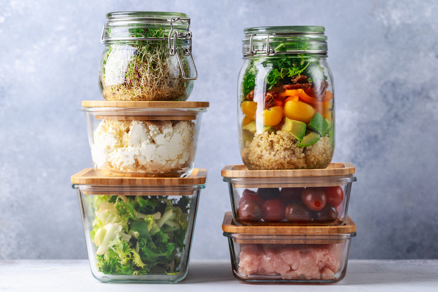 I contenitori di stoccaggio con cibo precotto sono impilati uno sopra l'altro davanti a una parete grigia