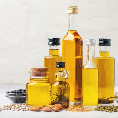 Olio fatto in casa  Gruppo di bottiglie di olio riempite in varie forme, disposte con semi di girasole, semi di zucca e semi di lino – ottimizzato per la visualizzazione mobile