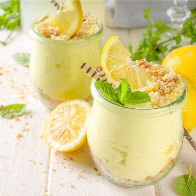 Immagine d'atmosfera: torta con crema al limone in un bicchiere decorato con menta e limoni