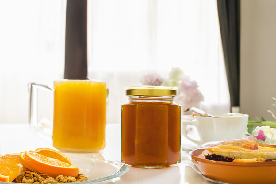Marmellata di arance Immagine d'atmosfera per la ricetta della marmellata di arance: barattolo di marmellata di arance su un tavolo apparecchiato per la colazione